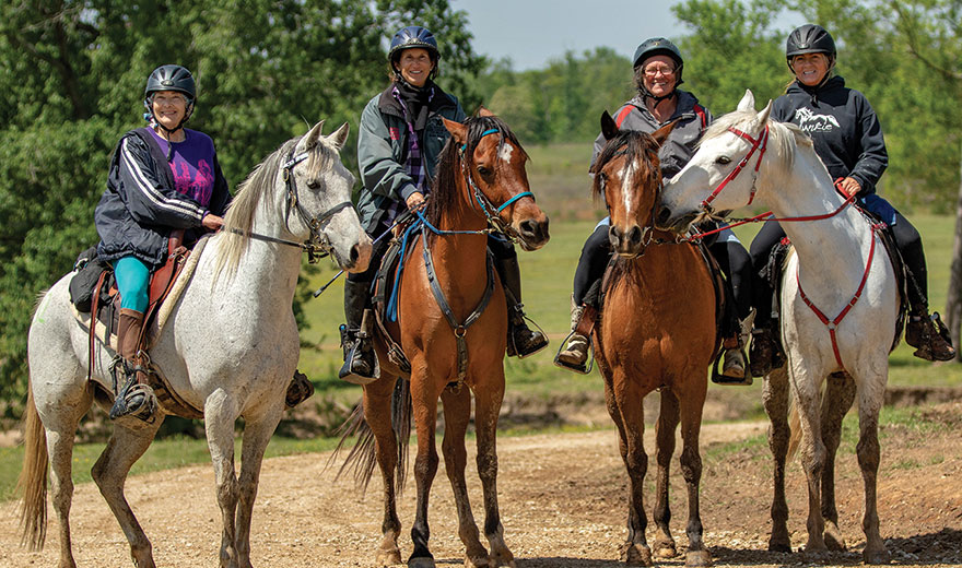 five riders at a water trough